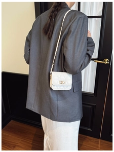 Chic quilted white crossbody bag with metal chain strap worn on grey oversized blazer