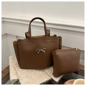 Close-up of brown bucket bag set with silver bow detail on an elegant wooden table