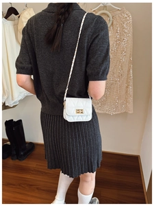 Detail of white quilted crossbody bag with golden twist lock and chain strap