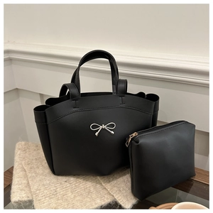 Detail of black leather tote bag with silver bow ornament and matching coin purse