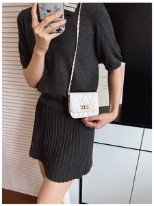 Close-up of a white quilted crossbody bag with gold hardware and chain strap