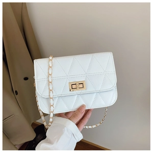 Detail of white quilted handbag with triangle stitching and elegant gold turn-lock closure