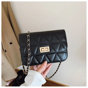 Detail of black quilted crossbody bag with gold twist lock and chain strap on person
