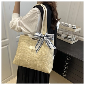 Detailed side view of beige woven tote bag with blue silk scarf accent on model