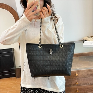 Large black tote bag with skull embossing and metal chain strap for daily commute