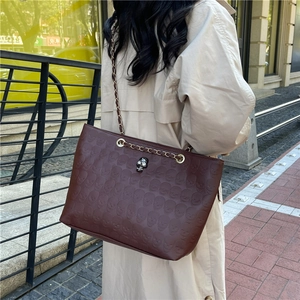 Deep brown oversized leather tote bag with skull embossing and silver skull hardware