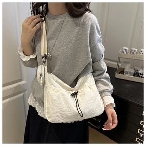 Detail of cream nylon crossbody bag with drawstring and small coin purse on shoulder strap