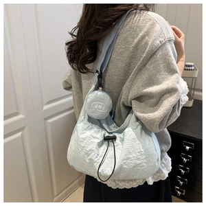 Detail of light blue nylon crescent crossbody bag with drawstring and mini round pouch