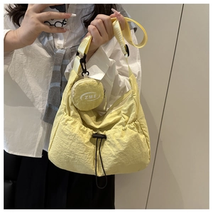 Detail of light yellow nylon crossbody tote bag with mini round coin purse and black drawstring