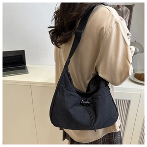 Detail of black nylon crossbody bag with drawstring design and adjustable strap