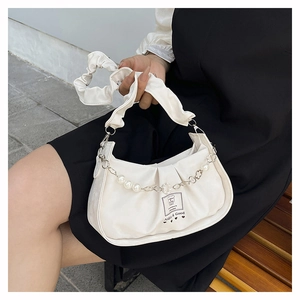 Détail du sac plissé blanc avec chaîne de perles et étiquette de marque Aldin & Good