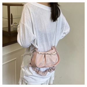 Detail view of pink pleated baguette bag with pearl chain and scrunched handle