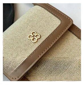Macro shot of beige canvas fabric with brown leather trim and clover metal logo