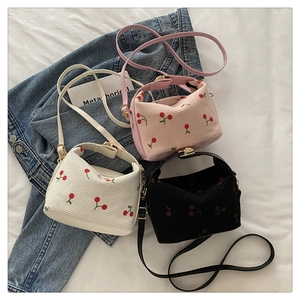 Detailed flat lay of corduroy shoulder bags with cherry print in pink, beige and black