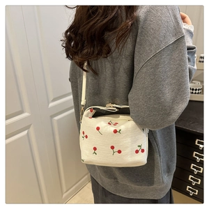Detail of white corduroy shoulder bag with red cherry embroidery and adjustable strap