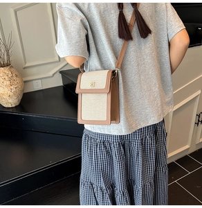 Détail d'un sac bandoulière crème et marron avec fermoir fleur dorée sur un mannequin