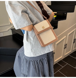 Détail du sac seau en toile avec bordure en cuir marron et logo pétale doré