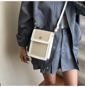 Detail of beige woven bucket bag with white leather trim and golden flower clasp