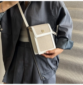 Detail of canvas mini bag with clover metal buckle and textured white leather trim