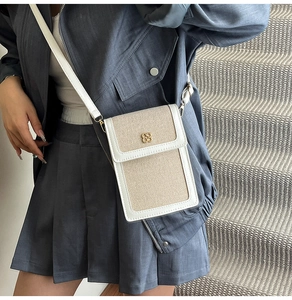 Detail of white leather and beige woven phone bag with golden clover metal hardware
