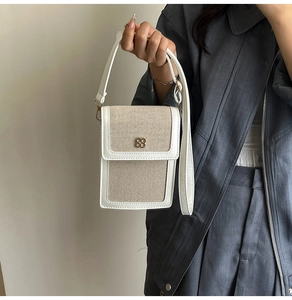 Détail du sac à bandoulière en toile et cuir avec boucle logo trèfle en métal doré
