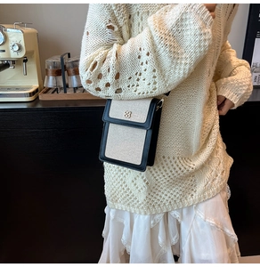 Canvas phone crossbody bag with black leather trim and gold clover logo on the front