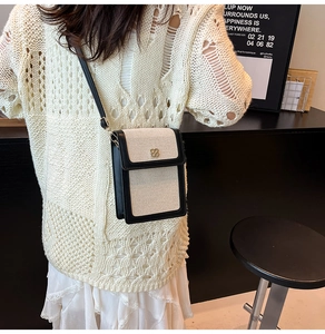 Minimalist canvas shoulder bag with black leather trim and golden clover metal clasp