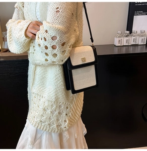 Détail d'un mini sac bandoulière en toile avec bordure en cuir noir et boucle trèfle dorée