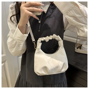 Detail of white pleated cloud bag showing micro-glossy leather texture and golden buckles