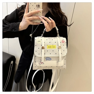 Detail of white polka dot handbag featuring playful patches and internal compartment