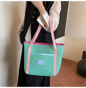 Detailed close-up of mint green mesh beach bag with pink handles and woven label logo