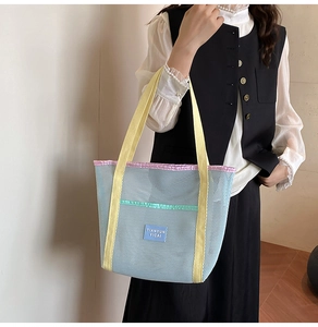 Detailed close-up of a mesh beach tote bag with colorful straps held by a model