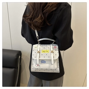 Detailed view of white crossbody bag with black polka dots and cartoon cat patches
