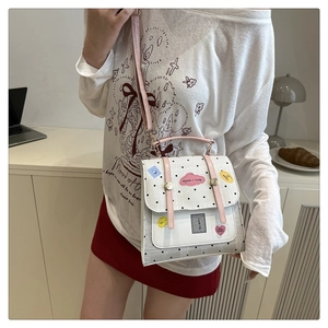 Detail of pink and white polka dot crossbody bag featuring cartoon stickers and straps