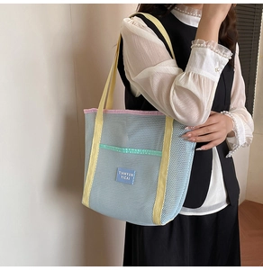 Detail of light blue mesh beach bag featuring vibrant yellow straps and mint green accent