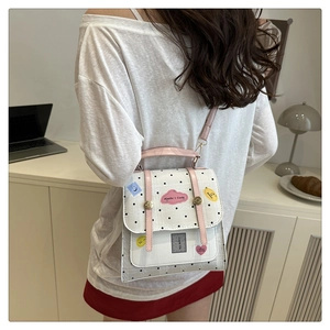 Detail view of polka dot square backpack with pink straps and cute patches on a desk