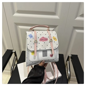 Detailed shot of white polka dot bag with pink straps and cute cartoon patch labels