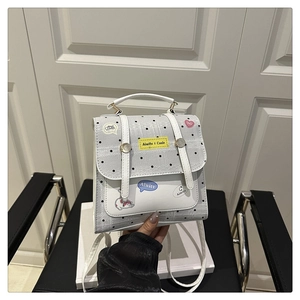 Detail of grey polka dot backpack with cartoon patches and adjustable shoulder straps