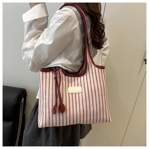 Detailed shot of large red and white striped canvas tote bag with leather straps on model