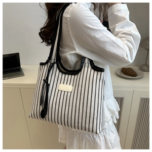 Détail du sac cabas en toile rayée avec anses en cuir dans un décor intérieur chaleureux