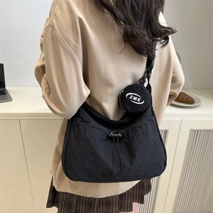 Black nylon crescent crossbody bag with drawstring closure and small round coin purse