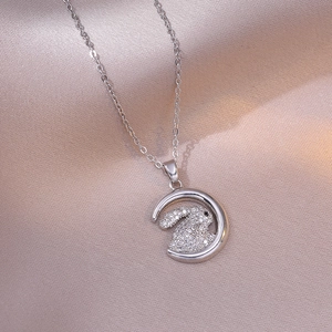 Elegant silver crescent moon and crystal rabbit pendant necklace on pink satin fabric