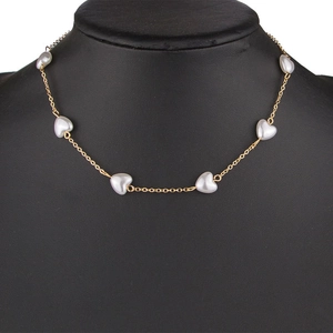 Collier doré élégant avec perles en forme de cœur exposé sur un buste de mannequin noir