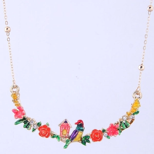 Detailed macro of enamel garden necklace featuring roses, a bird, and a cottage