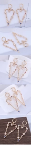 Detail view of large hollow heart earrings with colorful rhinestones and white pearls
