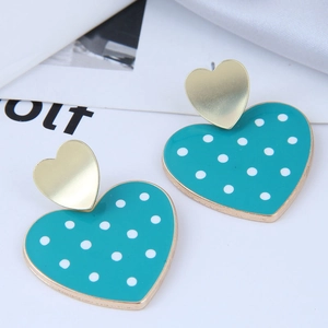 Détail de boucles d'oreilles cœur bleu sarcelle à pois blancs avec monture dorée élégante