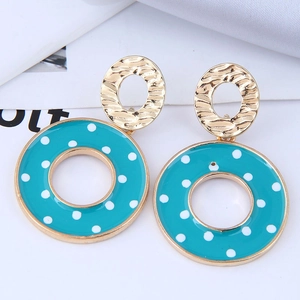 Détail de boucles d'oreilles dorées avec anneaux en émail bleu sarcelle à pois blancs