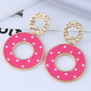 Vue détaillée de boucles d'oreilles dorées en émail rose à pois blancs sur satin