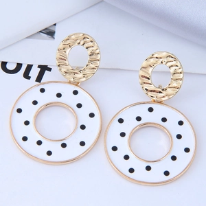 Détail de boucles d'oreilles ovales dorées avec pendentifs ronds à pois noir et blanc