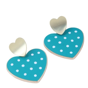 Boucles d'oreilles cœur dorées avec émail cyan et pois blancs sur un fond blanc épuré
